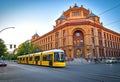 View of a large intersection with a historic post office in Berlin Mitte, with a tram in the foreground in the evening sun