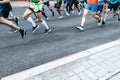 View of a large number of legs of runners in sneakers during a marathon through the city streets on asphalt