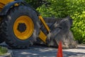 A view of a large wheel and bucket from a tractor, a yellow bulldozer that blocked the road, a roadway with a road sign Royalty Free Stock Photo