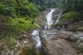 The view of Lata Iskandar Falls cascading down over and flowing between granite boulder with people at Cameron Highlands,