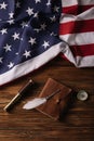 View of leather notebook, nib, telescope and compass on wooden surface with American national flag