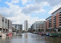 A view of of leeds dock with modern apartment developments and bars with moored houseboats and blue cloudy sky