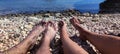 View of legs of young girl and boy on Croatian beach, pebble beach, lower part of human body, sea background