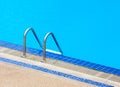 A view of a light clear blue swimming pool with steel ladder. Royalty Free Stock Photo