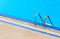 A view of a light clear blue swimming pool with steel ladder. Royalty Free Stock Photo