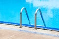 A view of a light clear blue swimming pool with steel ladder. Royalty Free Stock Photo