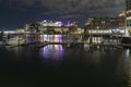 View of lights in the buildings at night seen from Boston Harbor deck. Horizon over the water