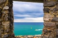 View of Ligurian sea water, rock cliff of Palmaria island and boat through brick stone wall window, Portovenere Royalty Free Stock Photo