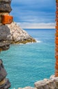 View of Ligurian sea water and rock cliff of Palmaria island through brick stone wall window of Portovenere Royalty Free Stock Photo