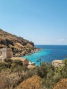 View of Limeni village with fishing boats in turquoise waters and the stone buildings as a background in Mani, Greece