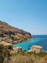 View of Limeni village with fishing boats in turquoise waters and the stone buildings as a background in Mani, Greece