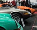 View of the lineup of a green Porsche 911, a silver Ferrari Daytona, and an orange Lamborghini Miura