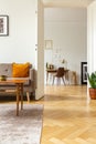 View from the living room with herringbone parquet floor into a home office interior with golden organizer above a wooden desk