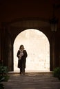 View of lone female entering a building from a lane via steps and an arched entrance