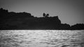 Silhouette of a lonely man sitting and fishing on the cliffs at sunset Royalty Free Stock Photo