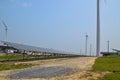 View of a long array of solar panels with two electric generating wind turbines in the background Royalty Free Stock Photo