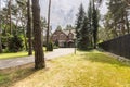 A view of a long paved driveway with grass, trees and evergreens