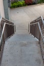 View looking down a narrow flight of concrete stairs with stainless steel railings