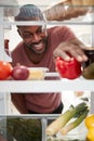 View Looking Out From Inside Of Refrigerator As Man Opens Door And Unpacks Shopping Bag Of Food Royalty Free Stock Photo