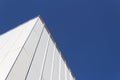 View looking up at corner of white generic building facade against a very deep blue sky