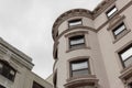 View looking up at rounded corner detail of a painted brick brownstone apartment building