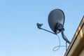 View looking up at a satellite dish on the roof of a generic building silhouetted against a blue sky, copy space, horizontal Royalty Free Stock Photo