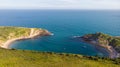 A view of the Lulworth Cove along the Jurrassic Coast in Dorset under a majestic blue sky and some white clouds Royalty Free Stock Photo