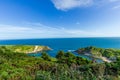 A view of the Lulworth Cove along the Jurrassic Coast in Dorset under a majestic blue sky and some white clouds