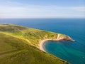 A view of the Lulworth Cove along the Jurrassic Coast in Dorset under a majestic blue sky and some white clouds