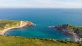 A view of the Lulworth Cove along the Jurrassic Coast in Dorset under a majestic blue sky and some white clouds