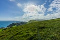 A view of the Lulworth Cove hill along the Jurrassic Coast in Dorset under a majestic blue sky and some white clouds