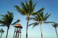 View at luxury resort hotel beach of tropical coast. Place of lifeguard. Leaves of coconut palms fluttering in wind