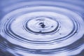 View macro of drops making circles on blue water surface isolated on background Royalty Free Stock Photo