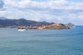 View from Magazzini Beach to the skyline and harbor with arriving ferry of Portoferraio, Elba island, Italy