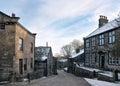 View of the main street in the village of Heptonstall in west Yorkshire with snow on roofs with blue winter sky