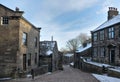 Main street in the village of Heptonstall in west Yorkshire with snow on roofs with blue winter sky