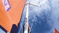 View of the mainsail, headsail, and mast of a sailboat against blue summer sky.