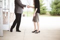 View of a male and a female wearing formal clothes while shaking hands, standing next to a building Royalty Free Stock Photo