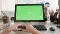 View on male hands working on a computer with green screen on a glass table