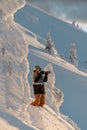 view of male photographer with photo camera among snow-covered fir trees on mountain slope. Royalty Free Stock Photo