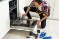 View Of Man In Overall Repairing Dishwasher In Kitchen Royalty Free Stock Photo