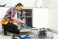 View Of Man In Overall Repairing Dishwasher In Kitchen Royalty Free Stock Photo