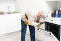 View Of Man In Overall Repairing Dishwasher In Kitchen Royalty Free Stock Photo