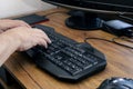 View of a man`s hands typing on his pc or computer keyboard at his home desk while working. Work at home concept Royalty Free Stock Photo