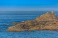 View of man sitting on the rocks reading the newspaper and sunbathing on yellow towel, ocean and blue sky as background Royalty Free Stock Photo