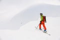 view of man skier with trekking poles walking along snowy mountain slope Royalty Free Stock Photo