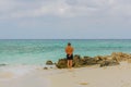 View of man standing on beach and looking on endless ocean. White sand beach and turquoise water merging with blue sky Royalty Free Stock Photo