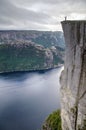 View of a man standing on the edge of Preikestolen Pulpit Rock with a fjord underneath