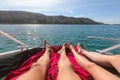 View on man and woman legs laying on yacht with tirquoise blue sea and beach with green palm trees on background. luxury Royalty Free Stock Photo