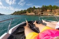 View on man and woman legs laying on yacht with tirquoise blue sea and beach with green palm trees on background. luxury Royalty Free Stock Photo